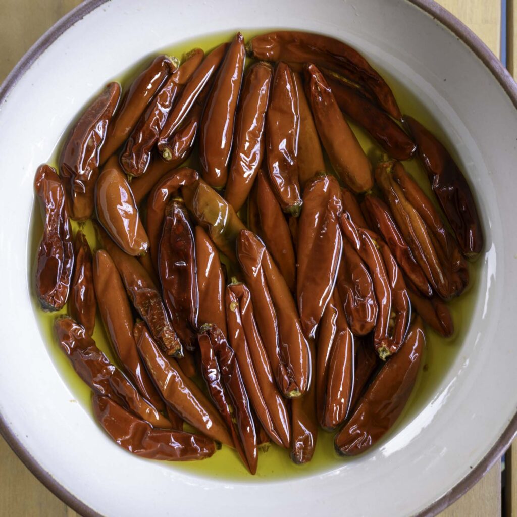 Closeup of Calabrian-style chiles swimming in chile-infused olive oil, ready to eat.
