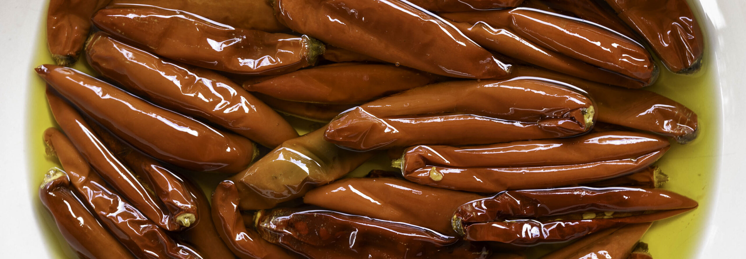 Closeup of Calabrian-style chiles swimming in chile-infused olive oil, ready to eat.