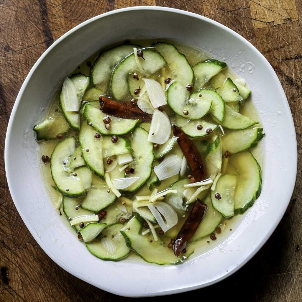Overhead view of Sichuan-style cucumber pickles in a shallow white bowl.