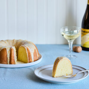 Mimosa pound cake served with a coupe glass of sparkling wine on a blue surface.