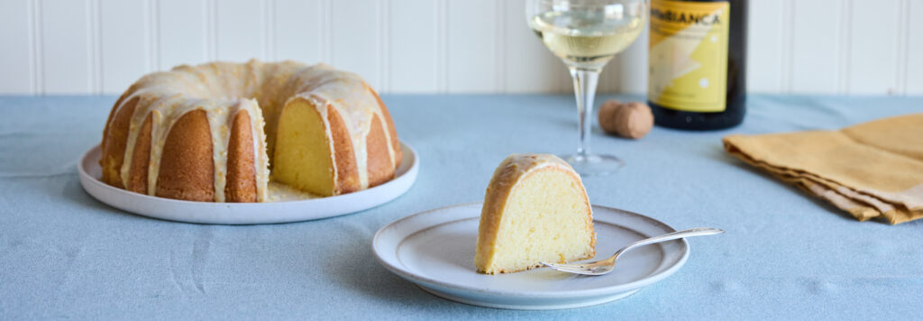Mimosa pound cake served with sparkling wine on a blue table cloth.