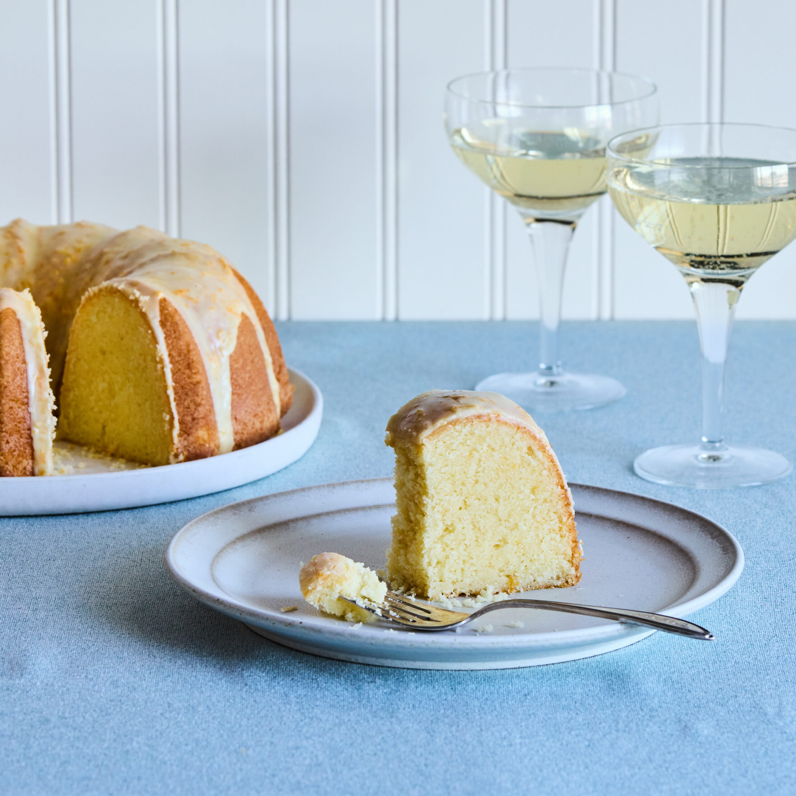 Closeup of mimosa pound cake slice. Some of the cake has been eaten and a bite remains on the tines of a fork set upon the rim of the cake plate.